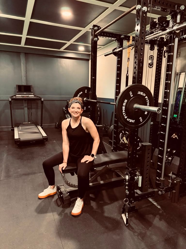 A woman resting on a weight bench mid-workout